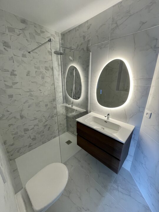 Salle de bain rénovée avec douche et miroir LED